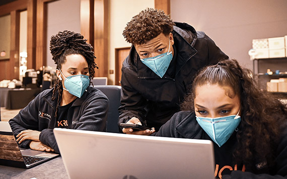 Three Krucial team members looking at a laptop