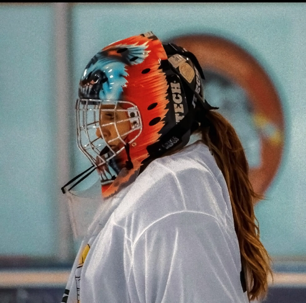 Hilary Seale in a hockey uniform with a goalie mask